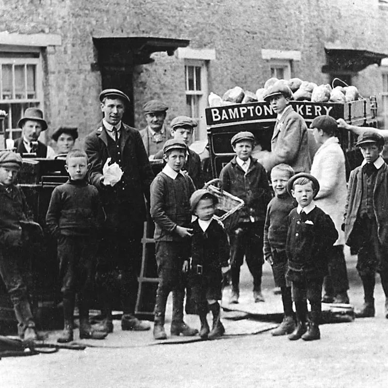 Black and white photograph of Bampton bakery cart with a crown of young men and children surrounding it.