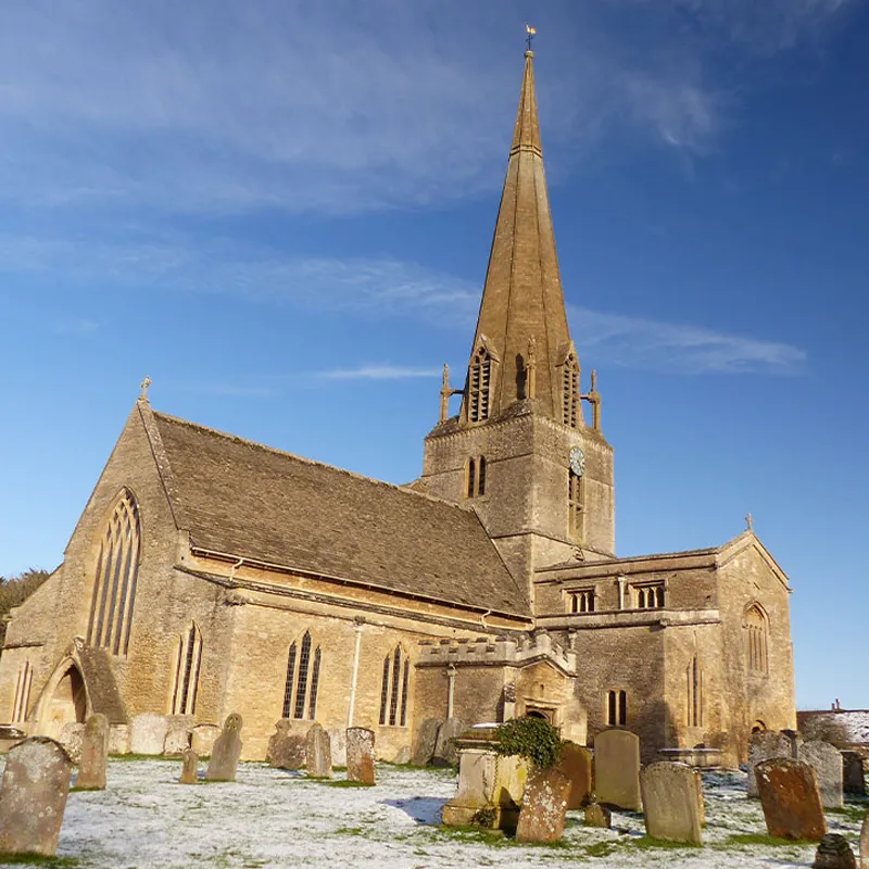 View of Bampton Church in blue skies and with frost over the grass.